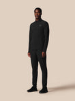 Man wearing a black outfit with a logo on a beige background