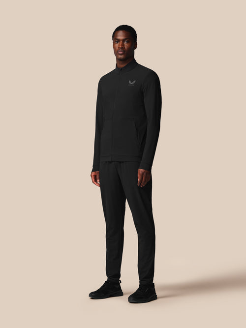 Man wearing a black outfit with a logo on a beige background