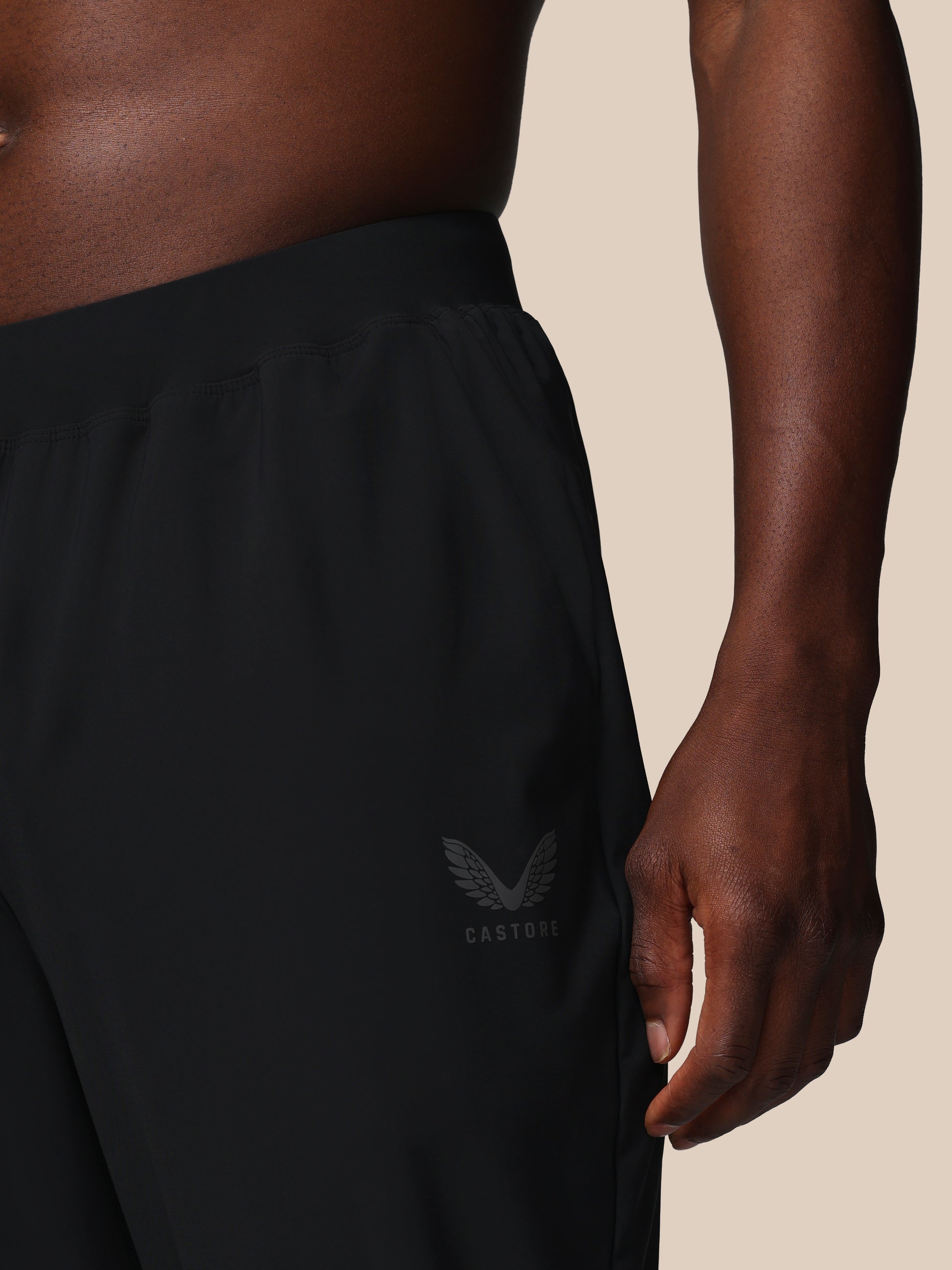 Person wearing black pants with a logo on a beige background