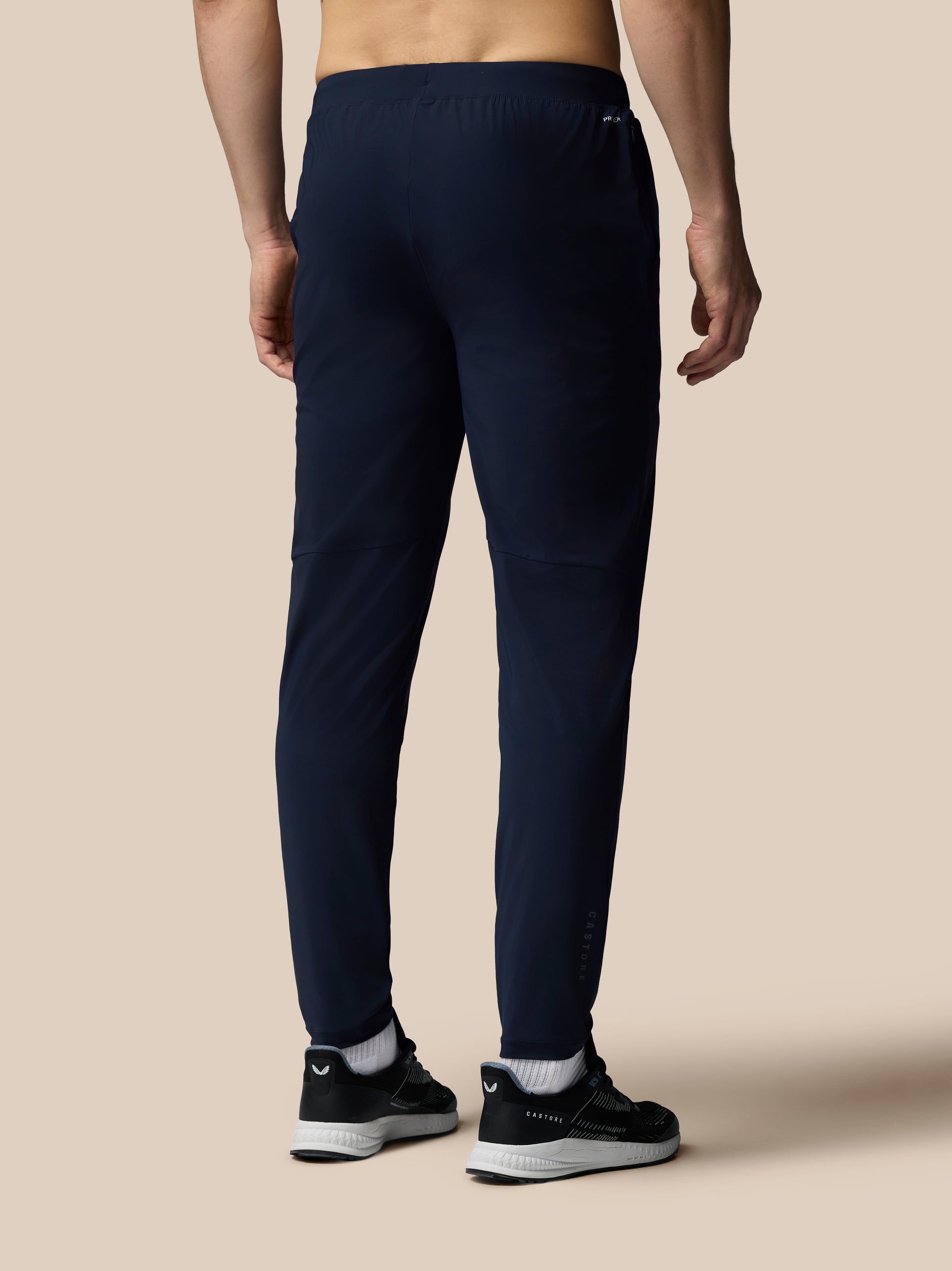 Person wearing navy jogger pants on a beige background
