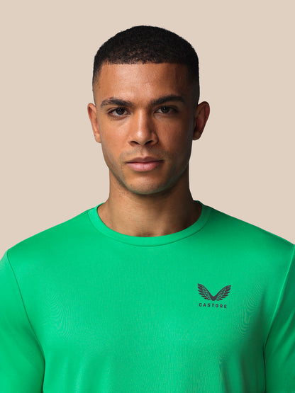 Man wearing a green t-shirt with a logo on a beige background