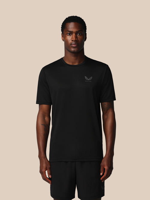 Man wearing a black t-shirt with a logo on a beige background