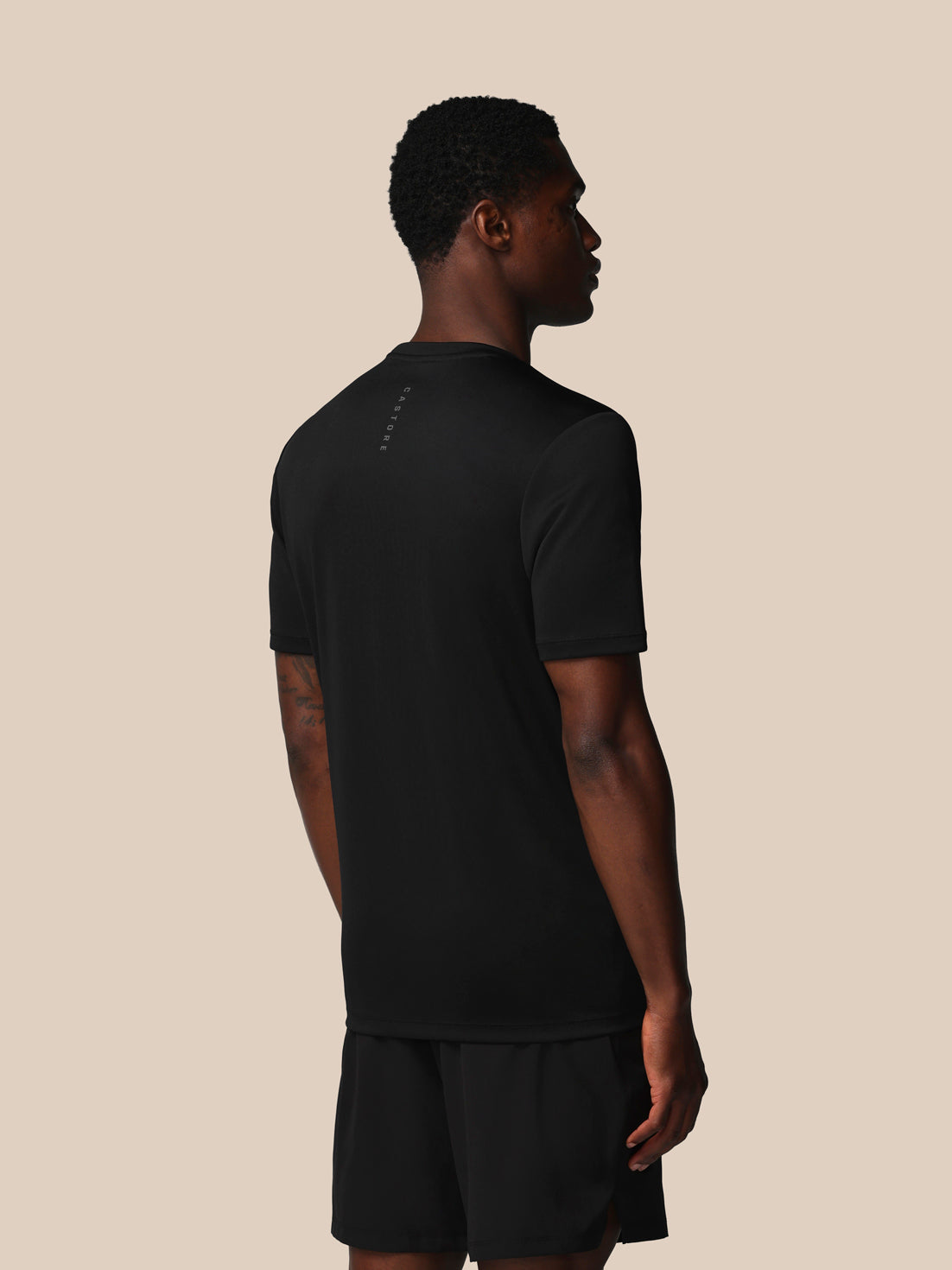 Man wearing a black t-shirt and shorts on a beige background