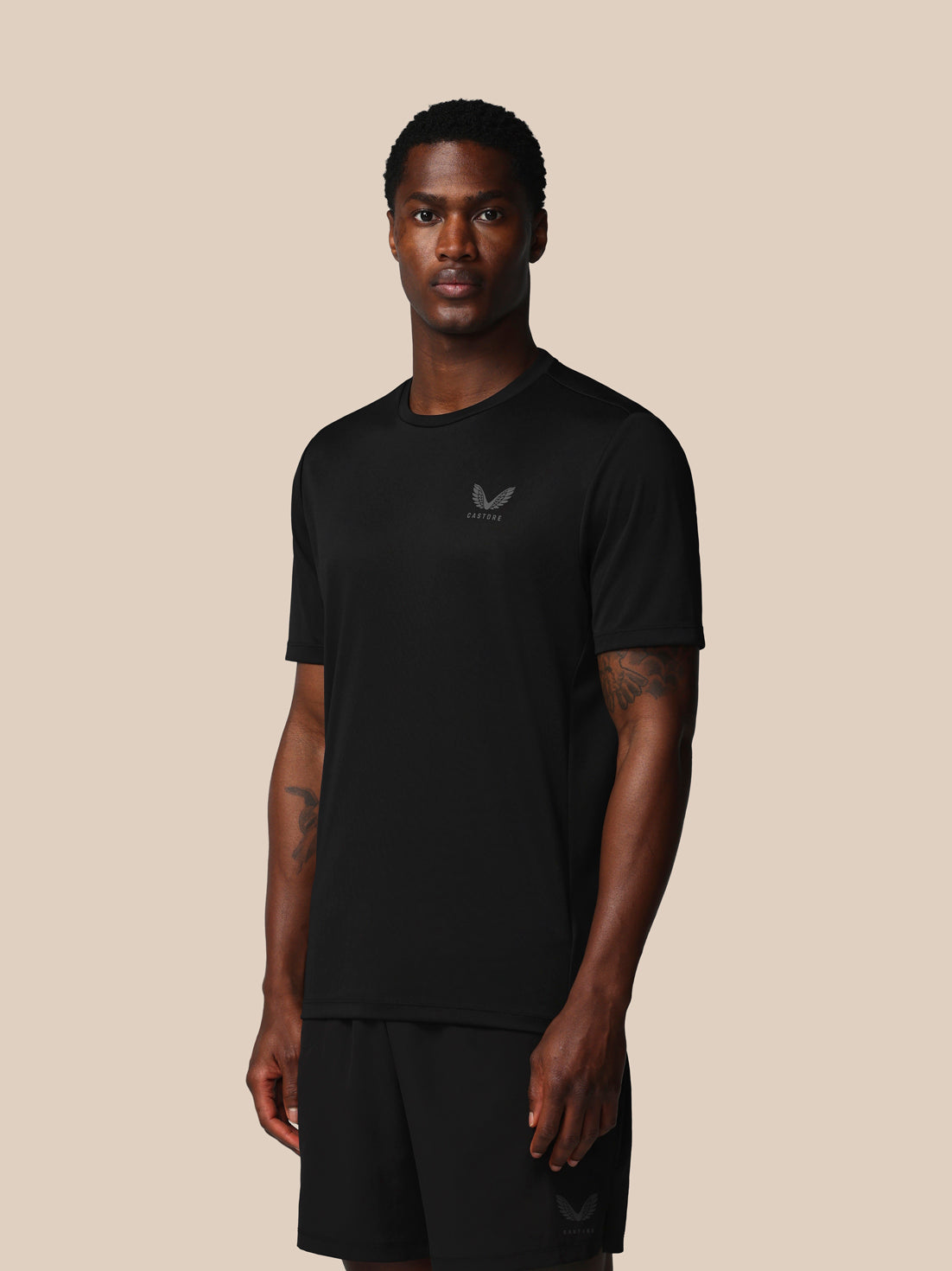 Man wearing a black t-shirt with a logo on a beige background