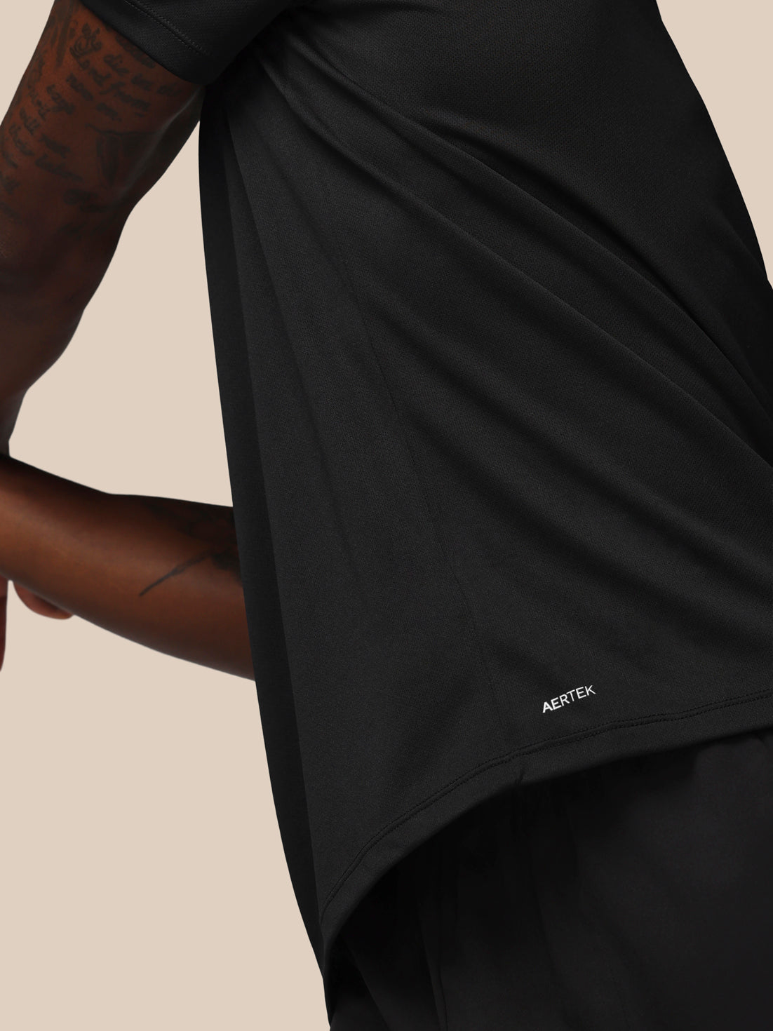 Black athletic shirt with 'AERTEK' logo on a beige background