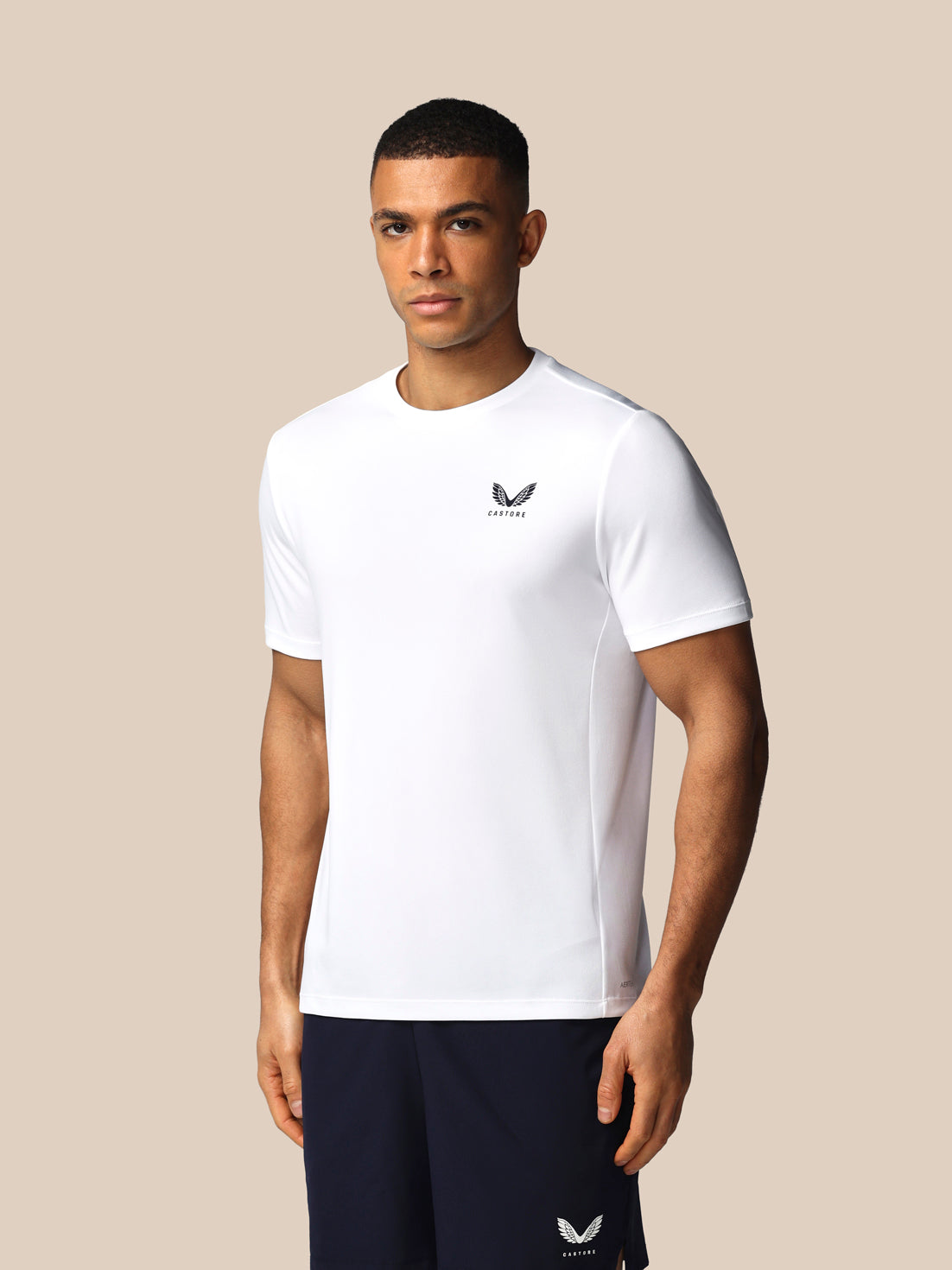 Man wearing a white t-shirt with a logo on a beige background