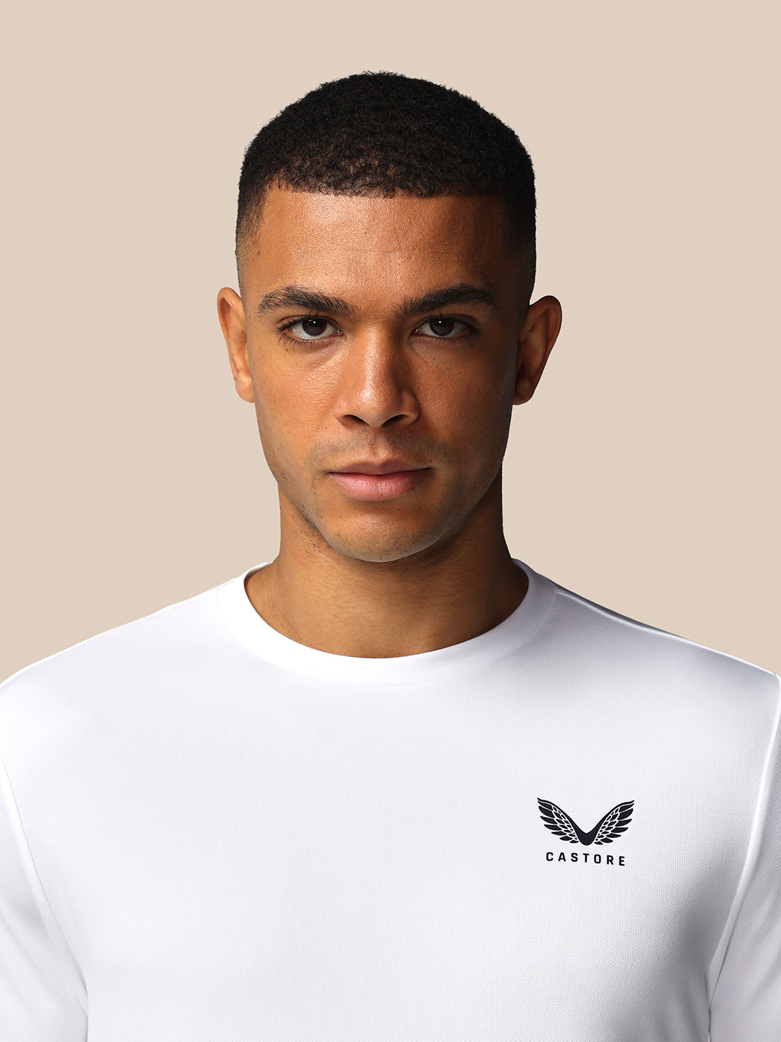 Man wearing a white t-shirt with a logo on a beige background