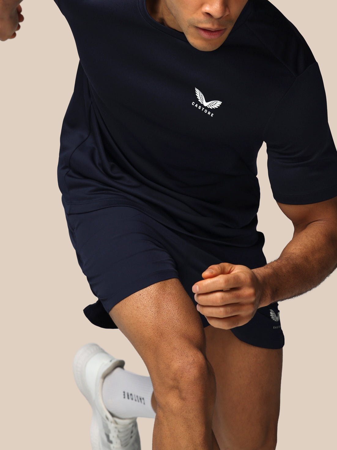 Person wearing a navy blue athletic outfit with a logo on a beige background
