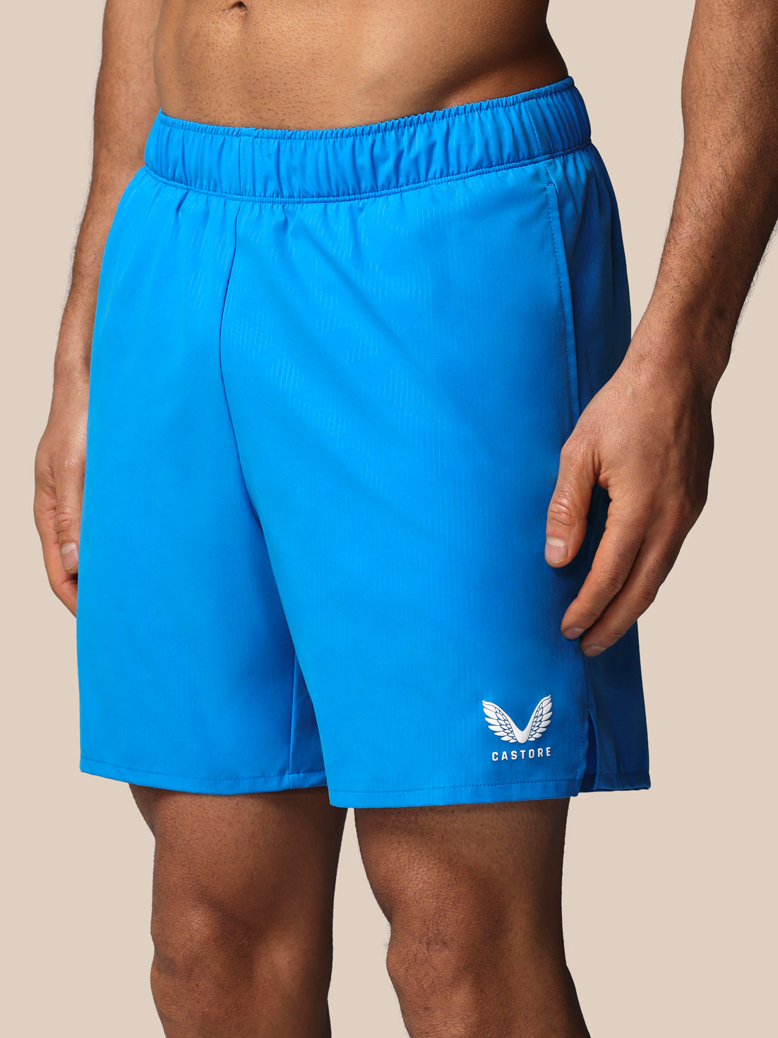 Blue athletic shorts with a brand logo on a beige background