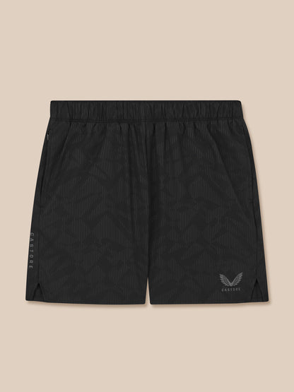 Black athletic shorts with a logo on a beige background