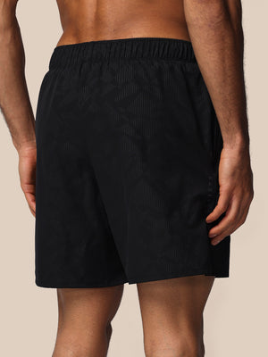 Black shorts worn by a person on a beige background