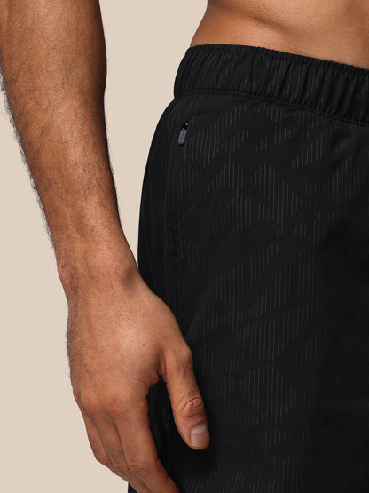Black athletic shorts worn by a person on a beige background