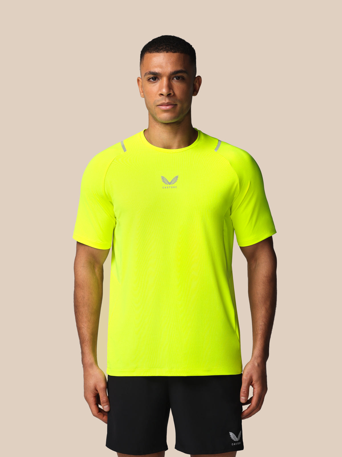 Person wearing a bright yellow athletic shirt with a logo on a beige background
