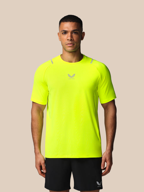 Person wearing a bright yellow athletic shirt with a logo on a beige background