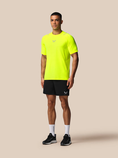 Man wearing a bright yellow athletic shirt and black shorts on a beige background