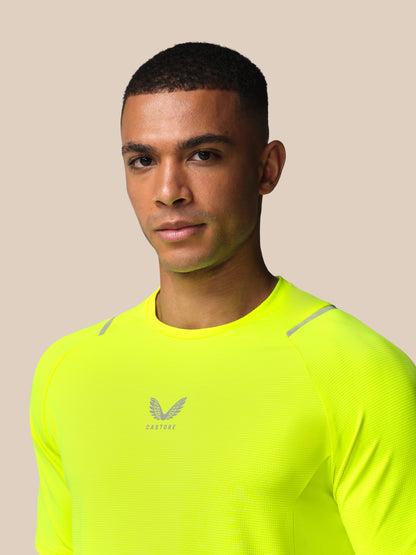 Man wearing a bright yellow athletic shirt with a logo on a beige background