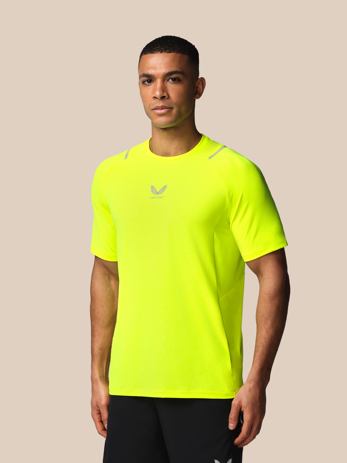 Man wearing a bright yellow athletic shirt with a logo on a beige background