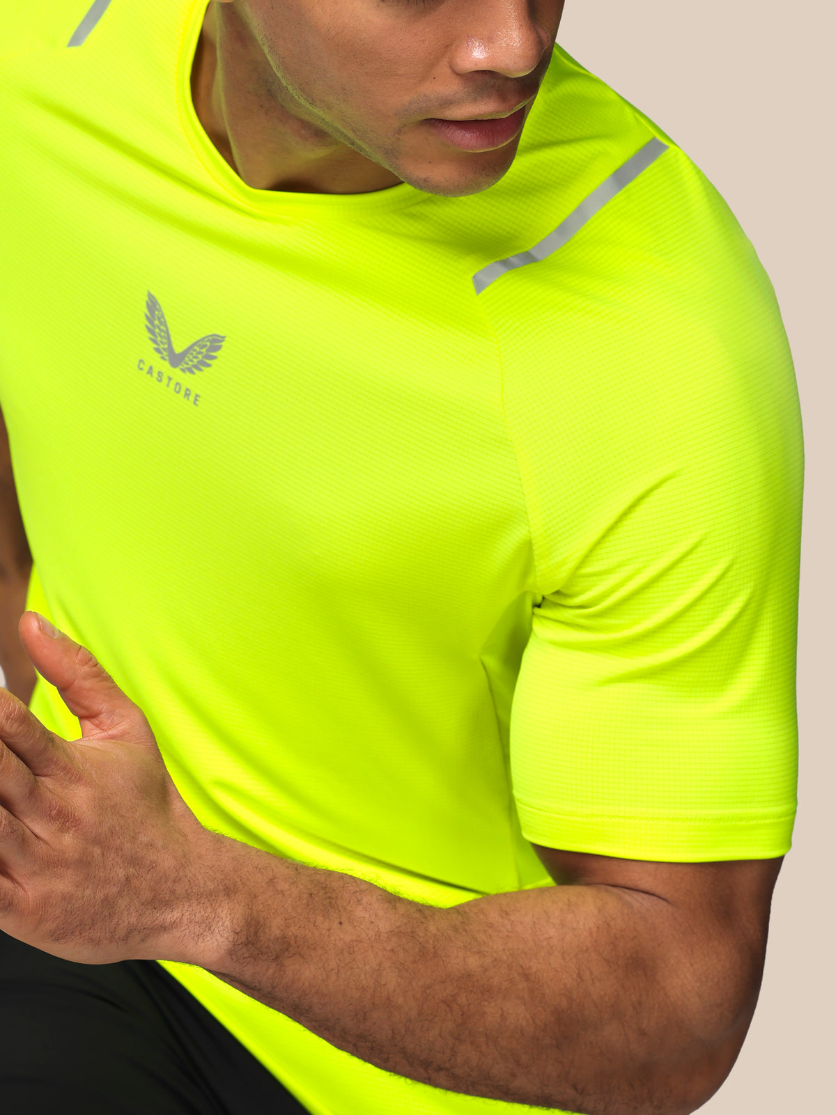 Person wearing a bright yellow athletic shirt with a brand logo on a beige background