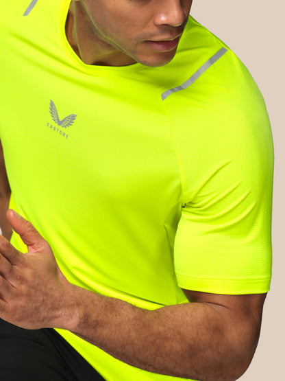 Person wearing a bright yellow athletic shirt with a brand logo on a beige background