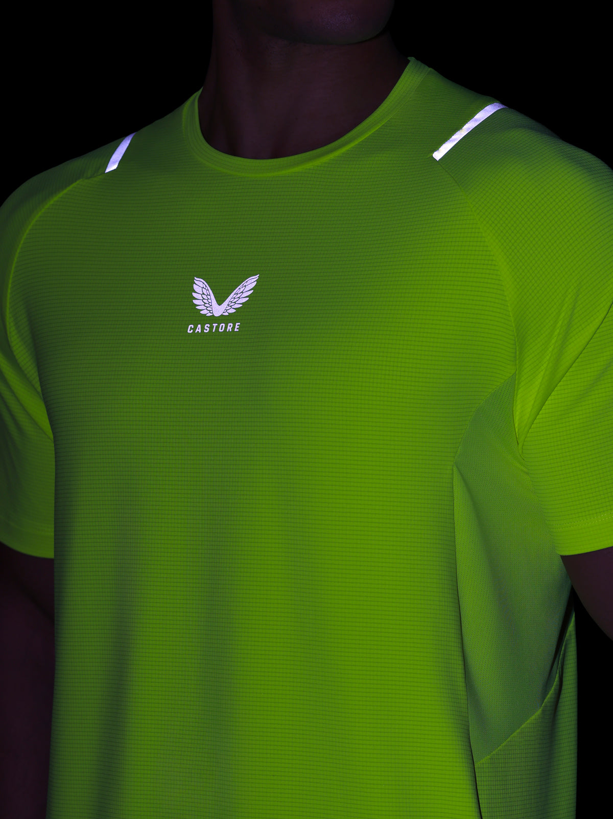 Green athletic shirt with a logo on a dark background
