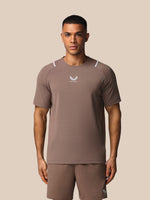 Man wearing a brown athletic outfit with a logo on a beige background