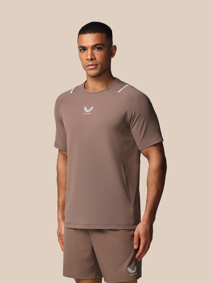 Man wearing a brown athletic outfit with a logo on a beige background