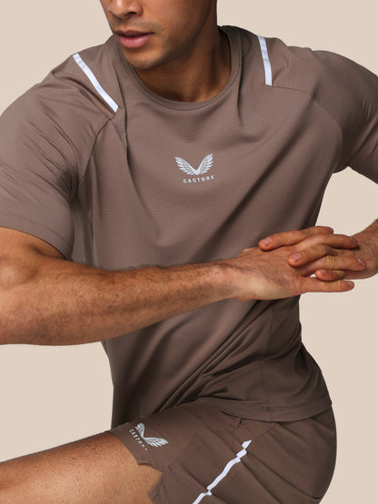 Man wearing a brown athletic outfit with a logo on a beige background