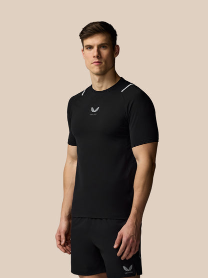 Man wearing a black athletic outfit with a logo on a beige background