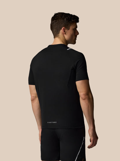 Man wearing a black athletic outfit with 'Castore' branding on a beige background