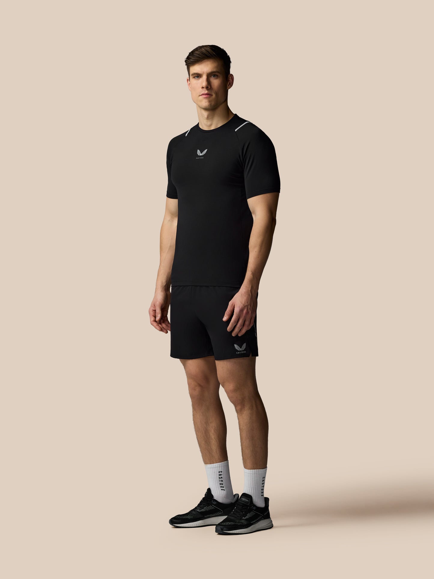 Man wearing a black athletic outfit with a logo on a beige background