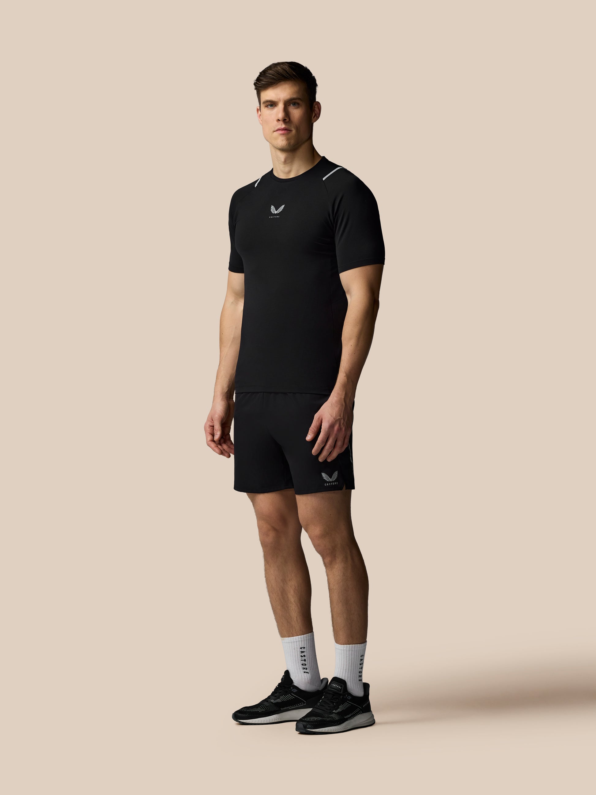 Man wearing a black athletic outfit with a logo on a beige background