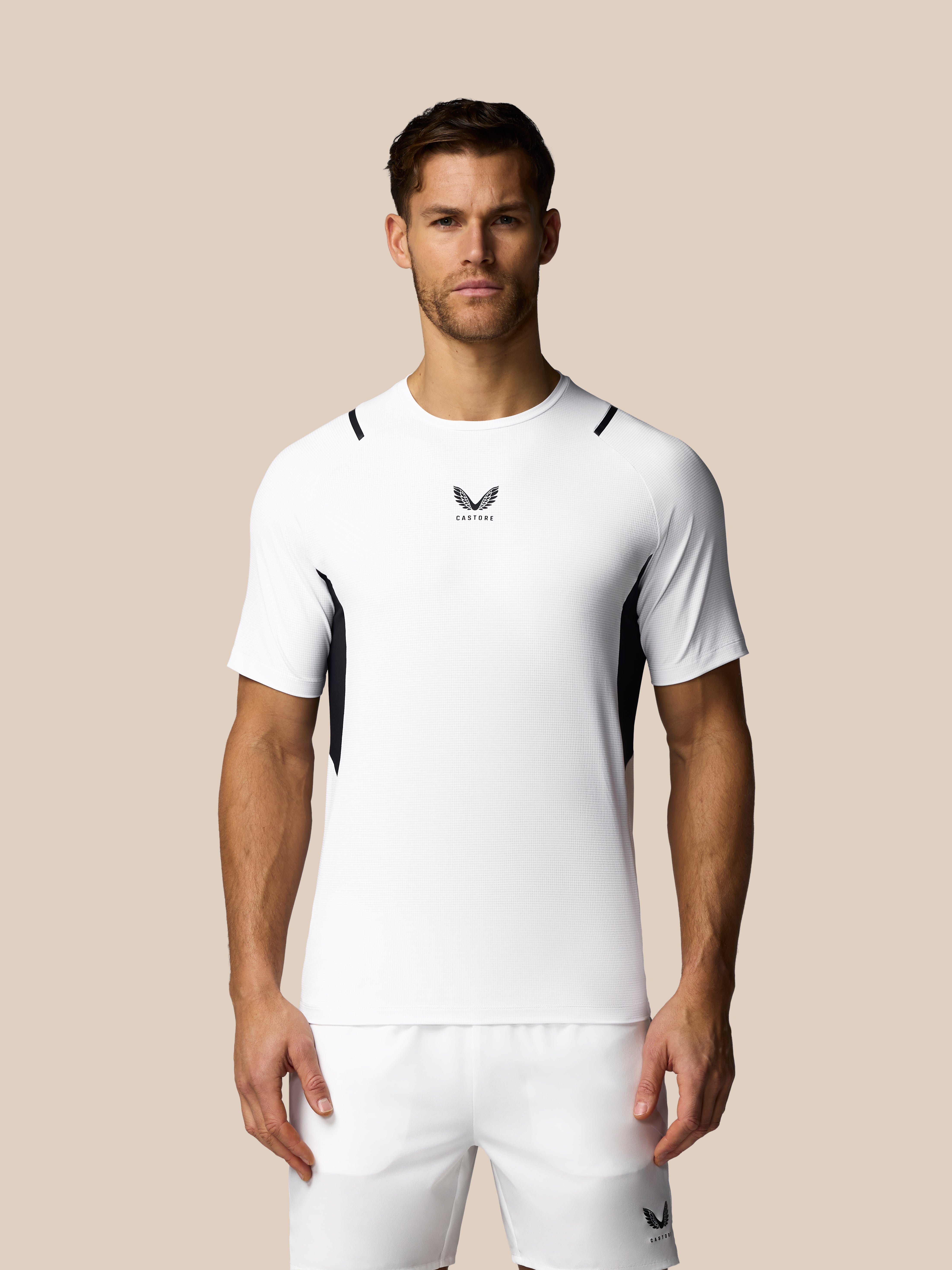 Man wearing a white athletic outfit with a logo on a beige background