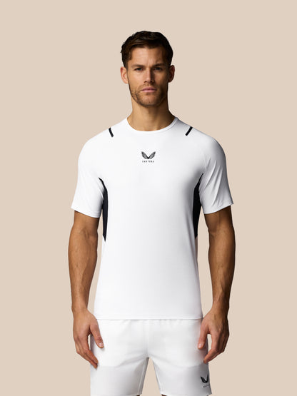 Man wearing a white athletic outfit with a logo on a beige background