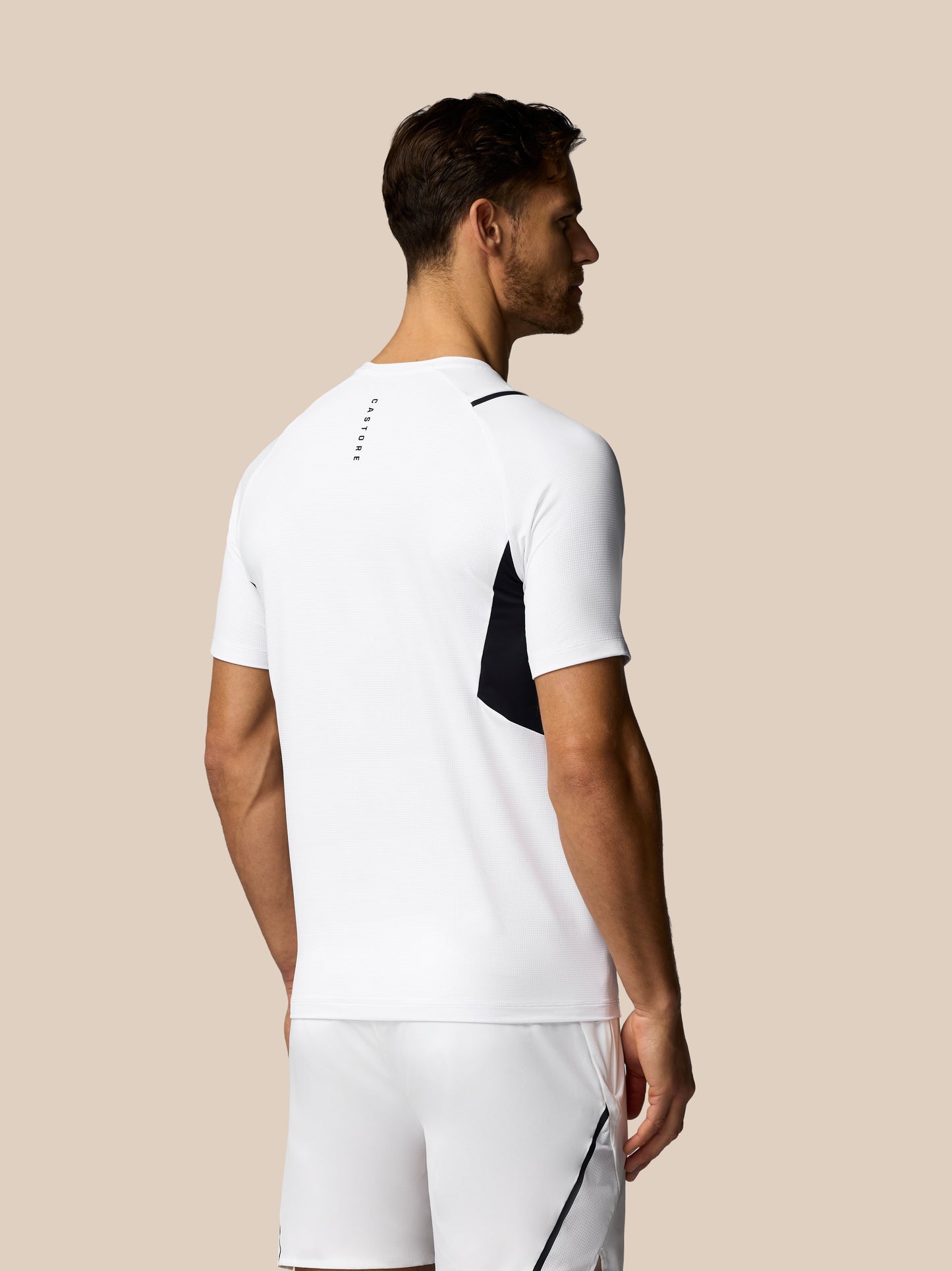 Man wearing a white athletic outfit with black accents on a beige background