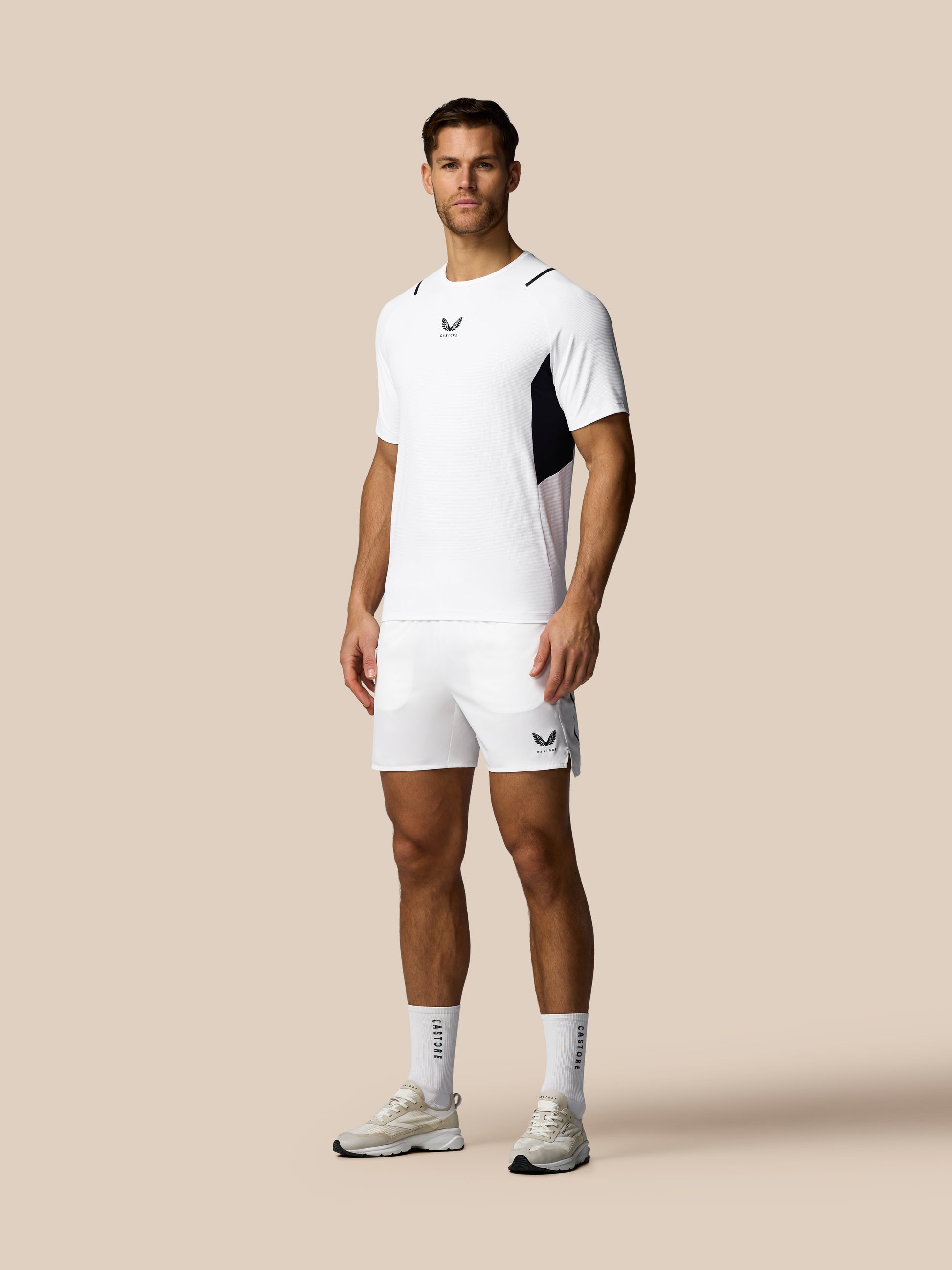 Man wearing a white athletic outfit with black accents on a beige background