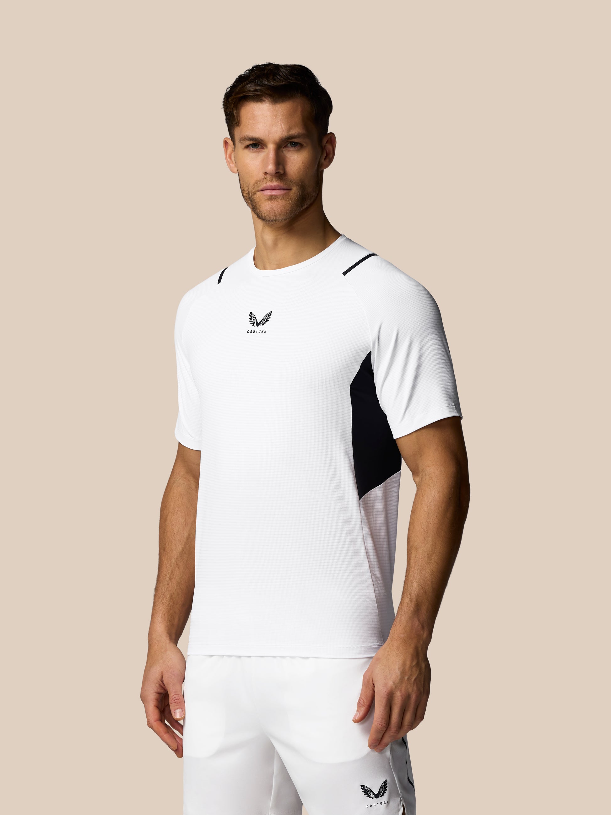 Man wearing a white sports outfit with a logo on a beige background