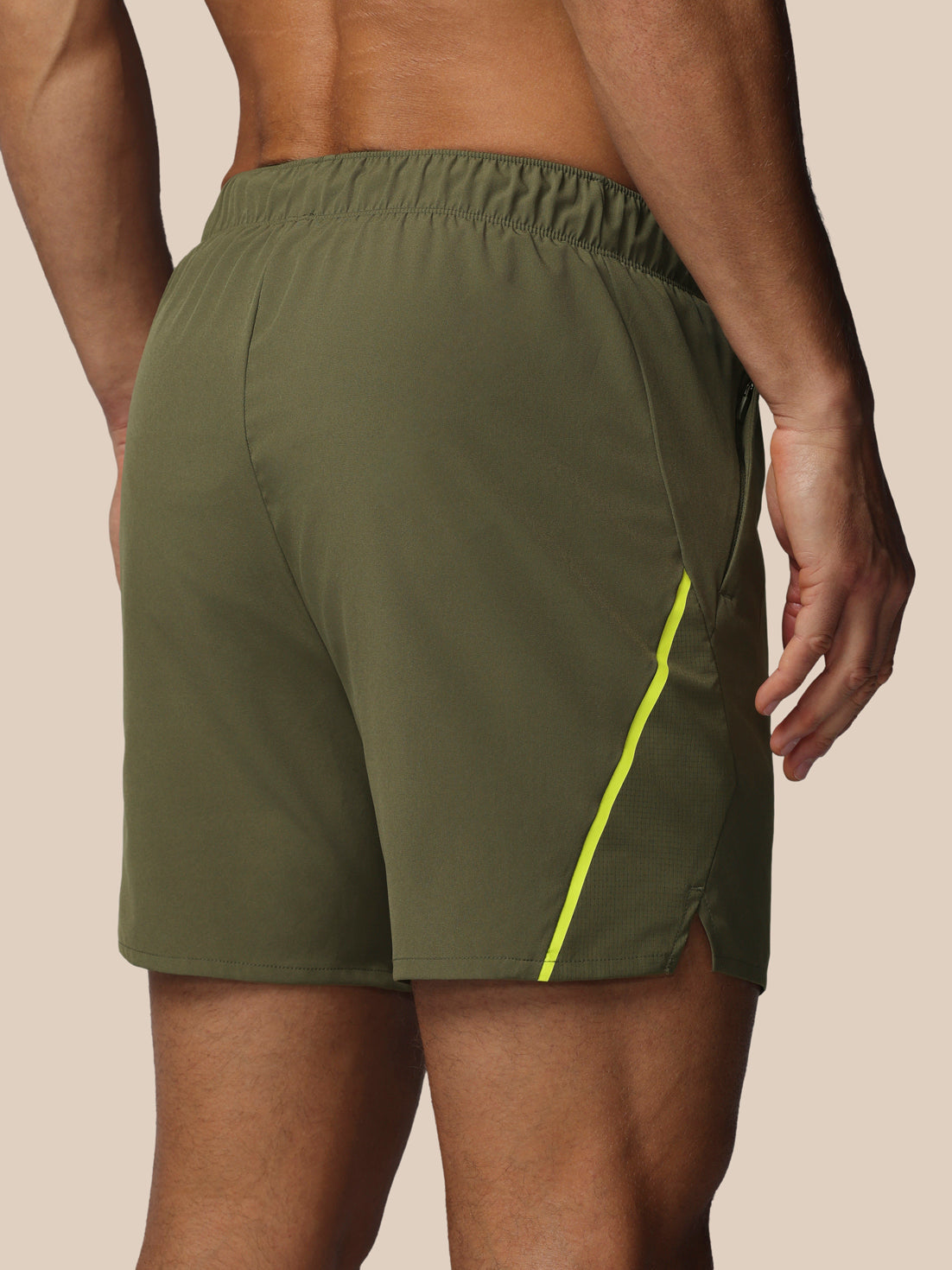 Green athletic shorts with a yellow stripe on a beige background