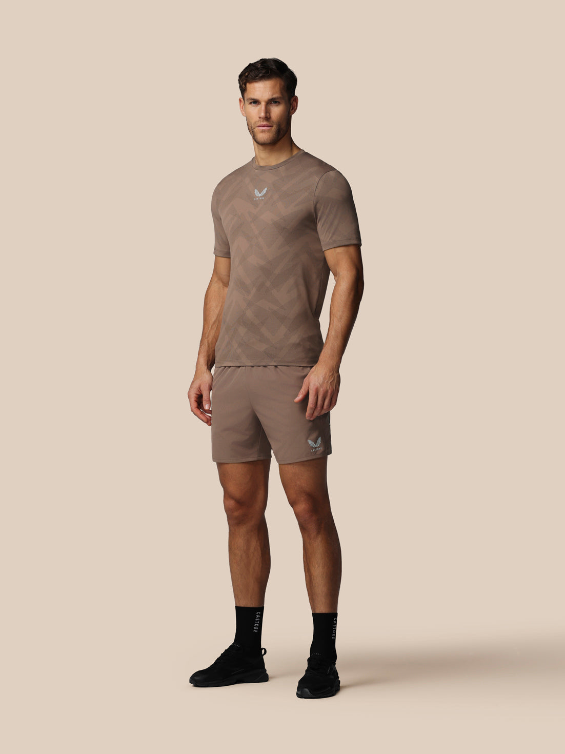 Man wearing a brown athletic outfit on a beige background