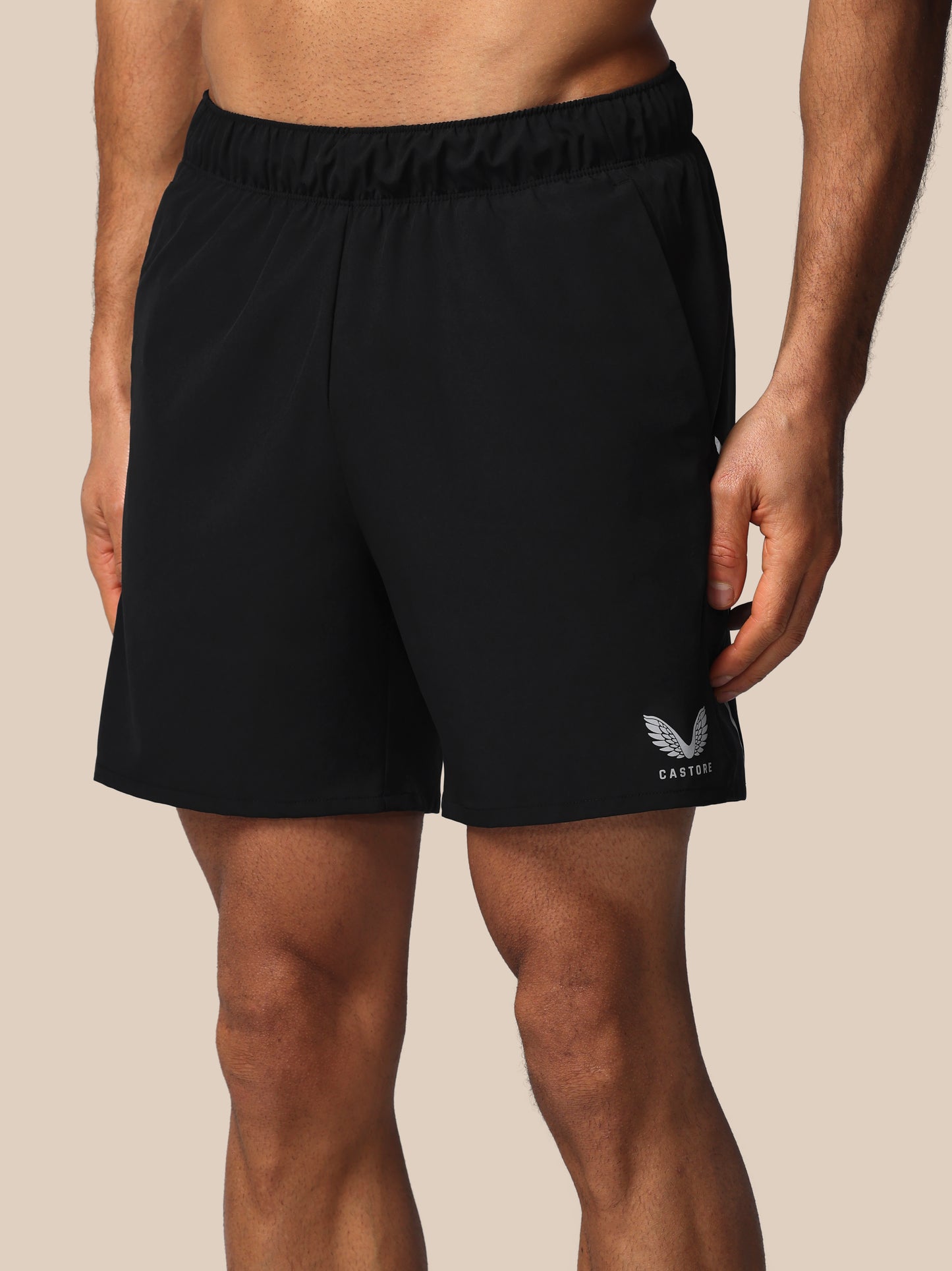Black athletic shorts with a logo on a beige background