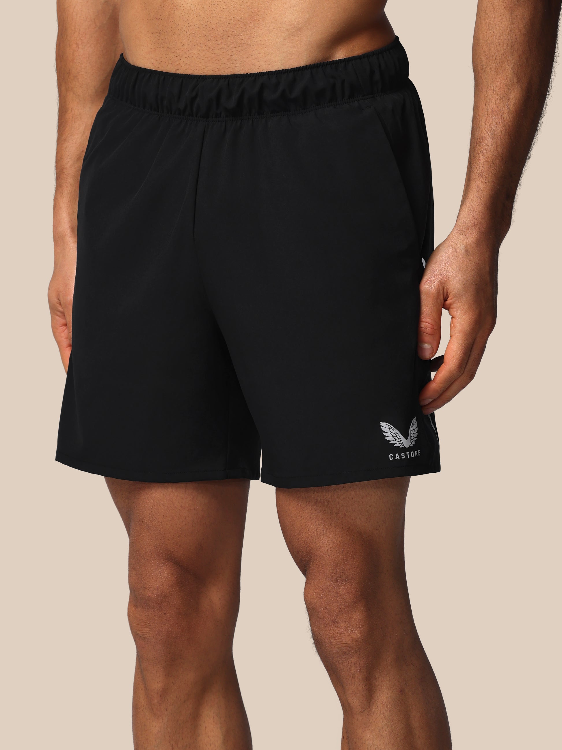 Black athletic shorts with a logo on a beige background