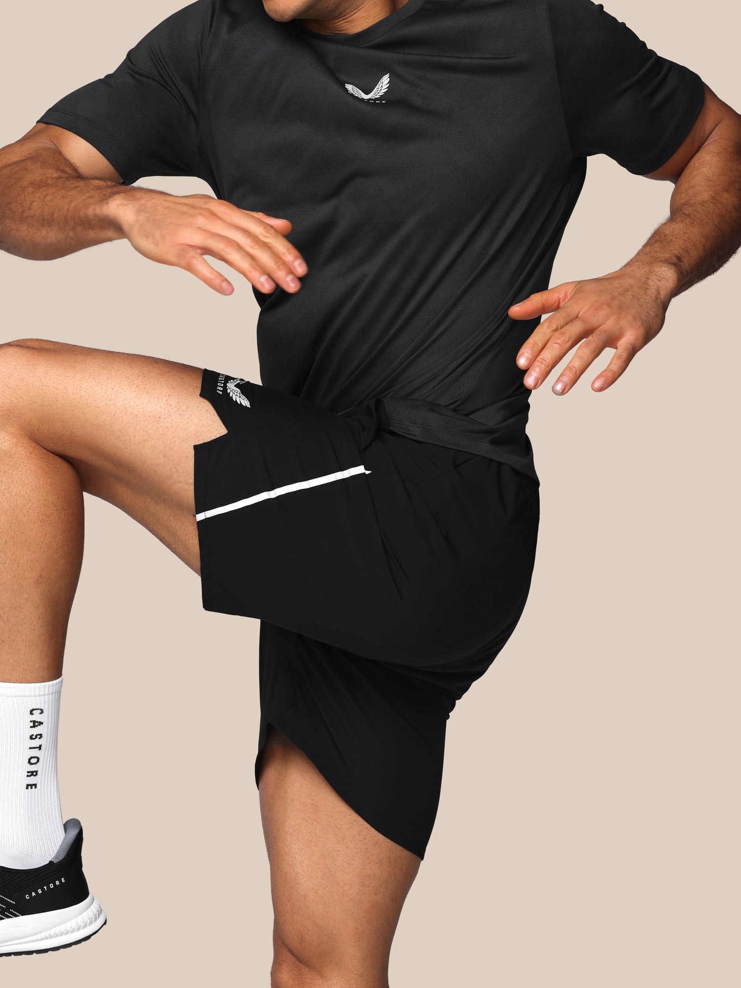 Person wearing black athletic outfit with a visible brand logo on a beige background