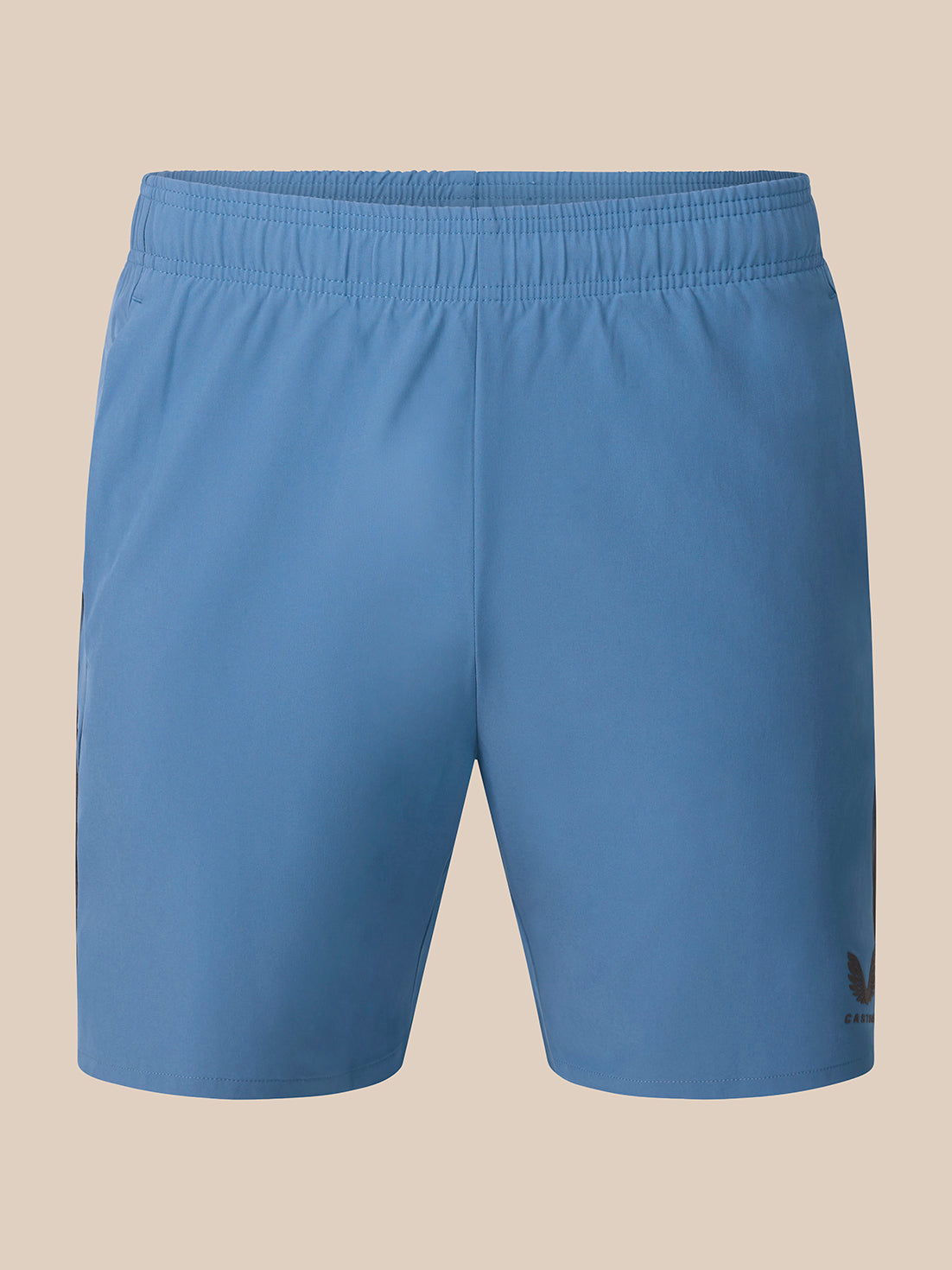 Light blue athletic shorts with an elastic waistband and a small black Castore logo on the lower left hem, shown against a solid beige background.