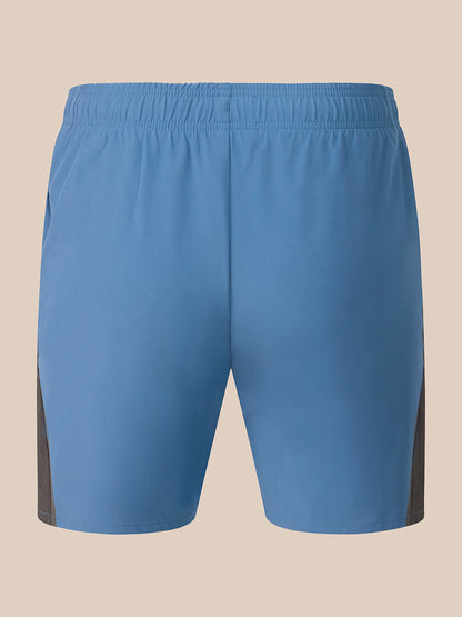 Light blue athletic shorts with dark gray side panels, shown from the back on a solid beige background.
