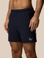 Navy athletic shorts with a logo on a beige background