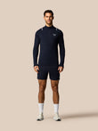 Man wearing a navy long-sleeve athletic shirt and shorts on a beige background