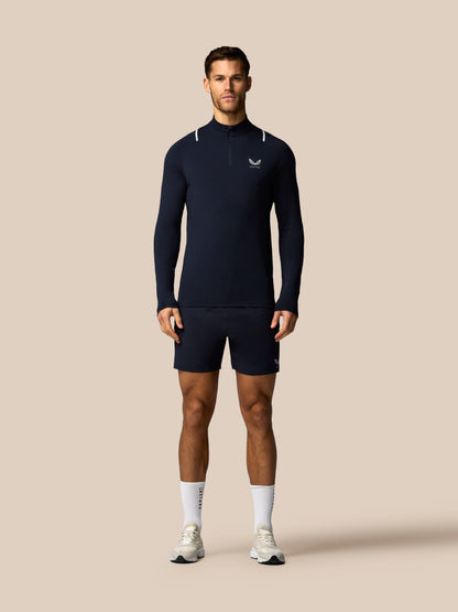 Man wearing a navy long-sleeve athletic shirt and shorts on a beige background