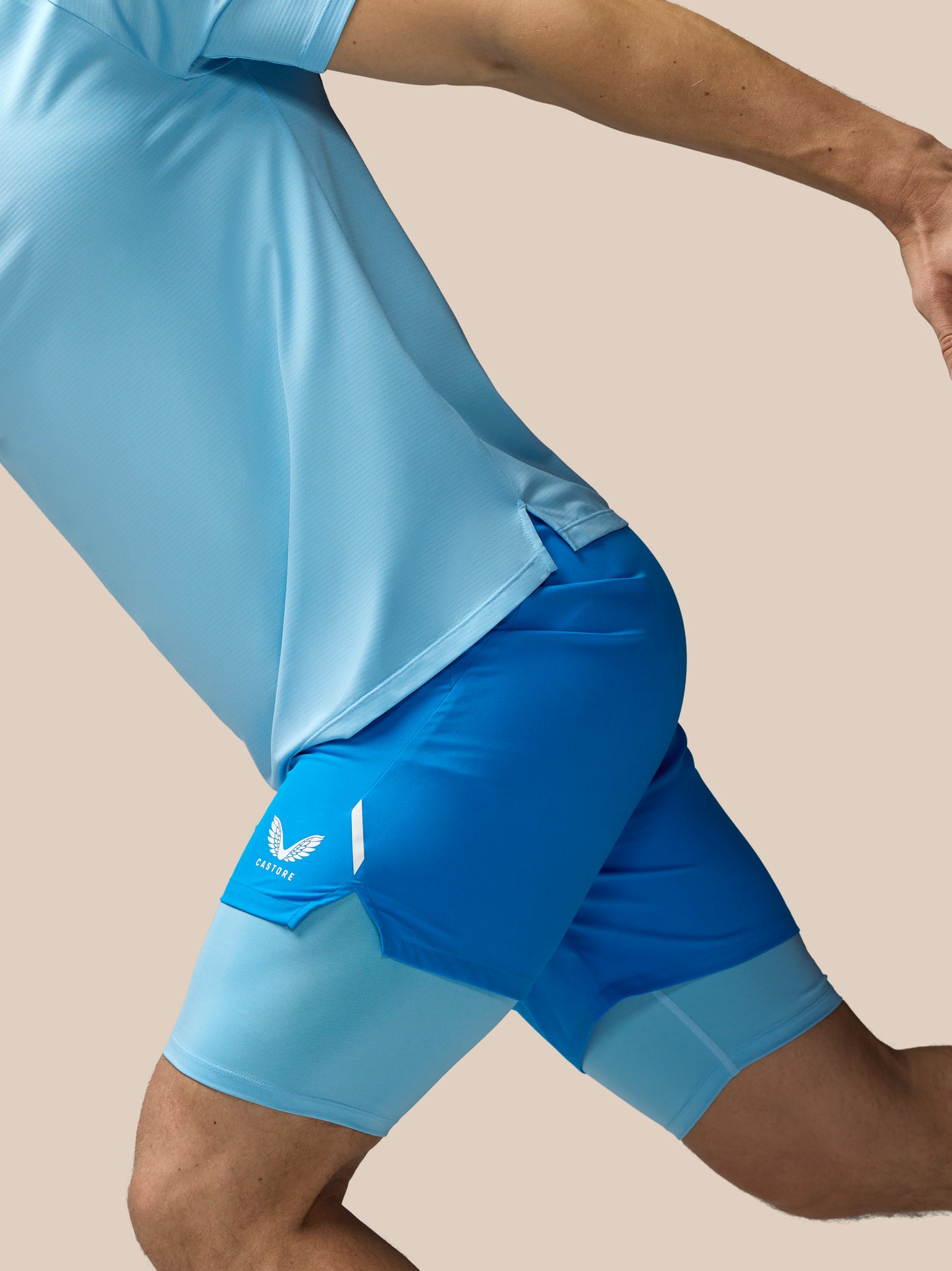 Person wearing blue athletic shorts with a logo on a beige background