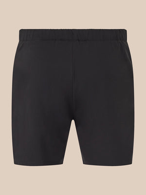 Black athletic shorts with an elastic waistband, shown flat against a solid beige background.