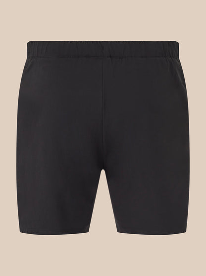 Black athletic shorts with an elastic waistband, shown flat against a solid beige background.