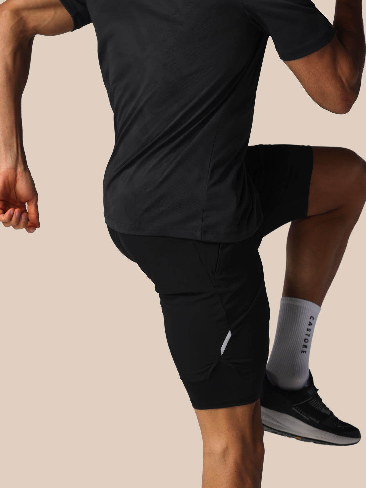 Person wearing black athletic shorts and a black shirt on a beige background